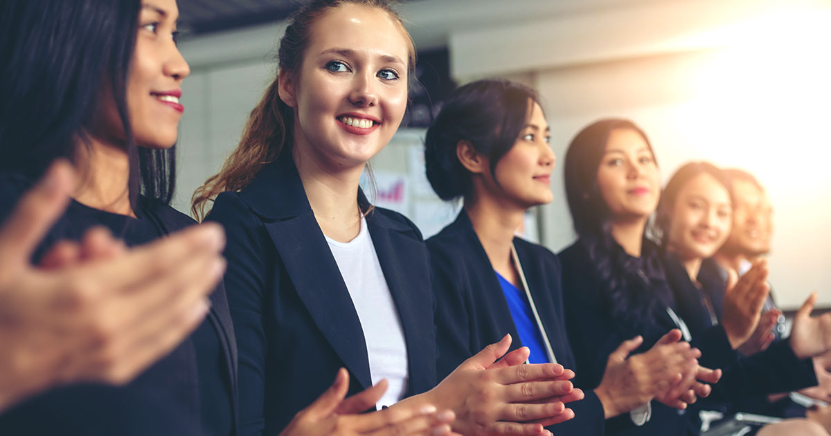 Women applauding at a business conference.