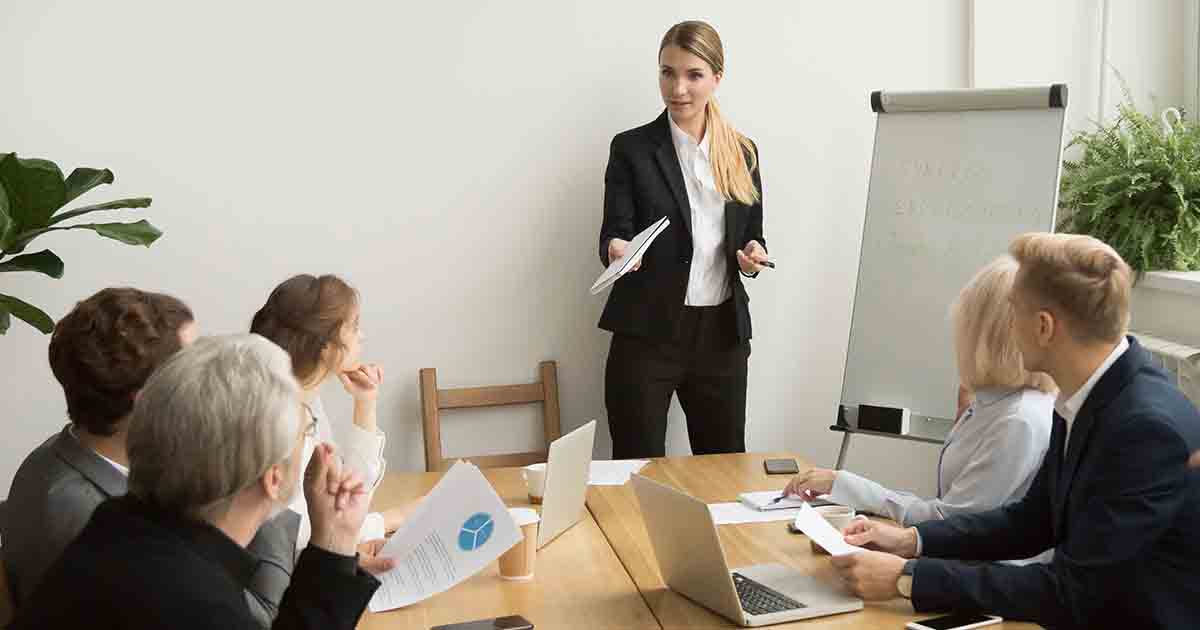 Woman business owner in suit presenting to her team.