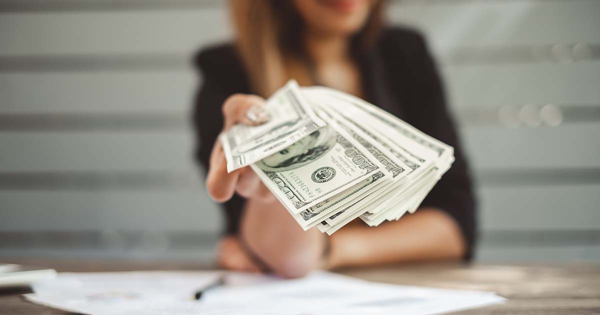 Business woman in office handing out cash.